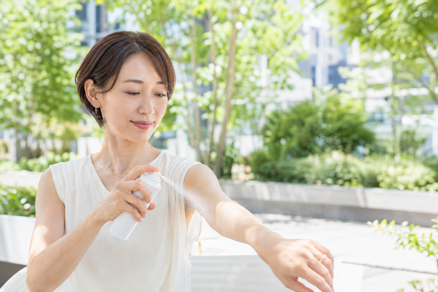 屋外で腕にUVスプレーを塗り直す女性